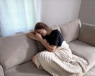 a woman sitting on a couch with her head on her hand