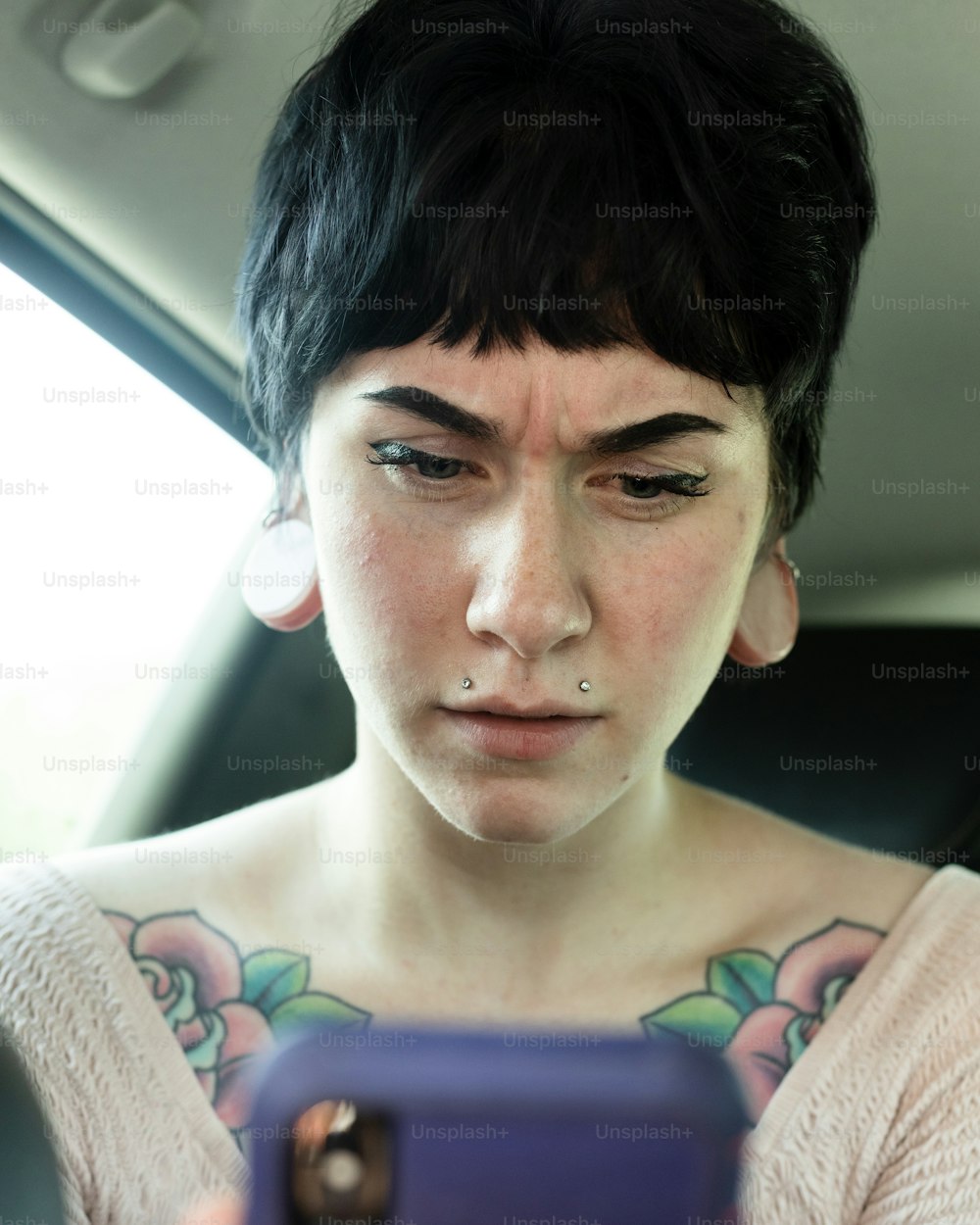 Eine Frau mit Piercings schaut auf ein Handy