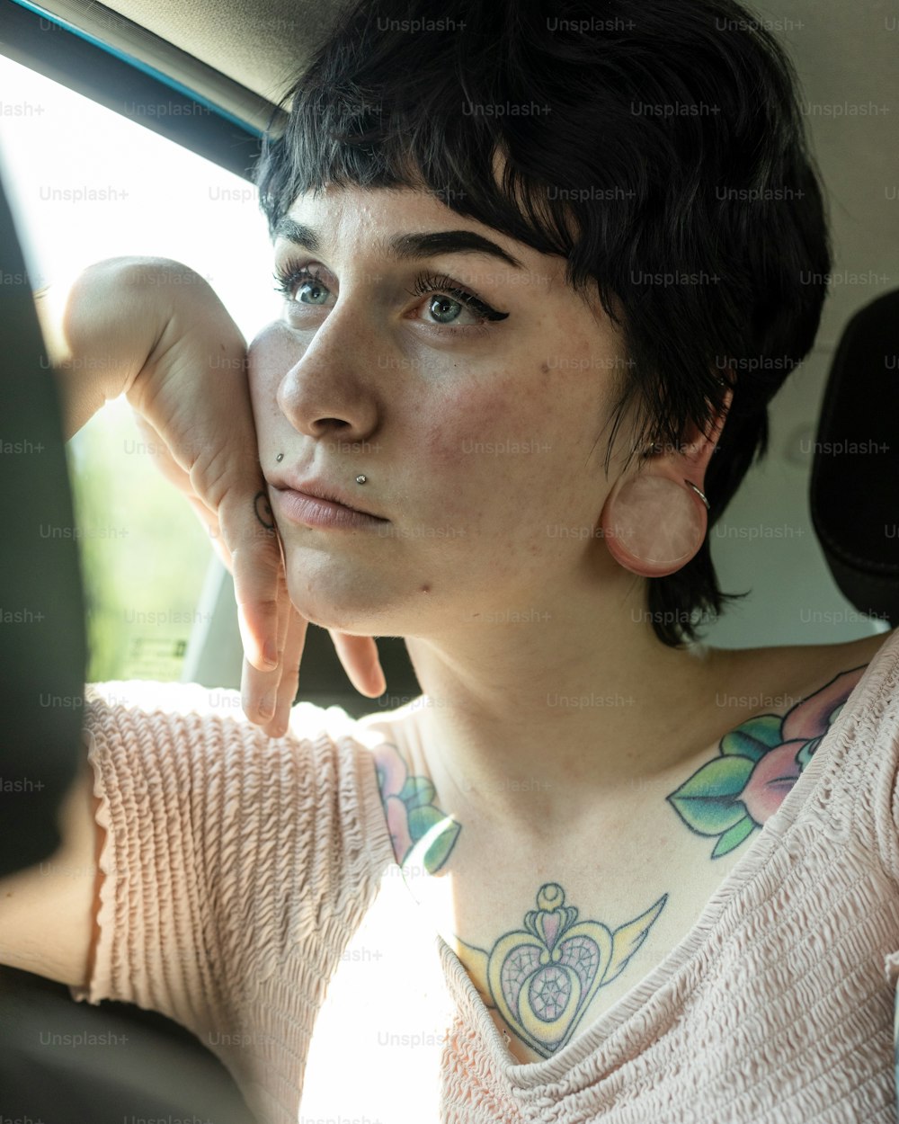 uma mulher com uma tatuagem no pescoço sentada em um carro