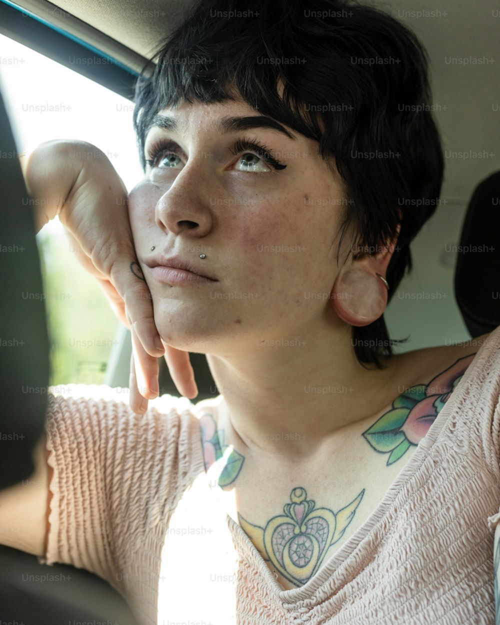 a woman sitting in a car with a tattoo on her neck