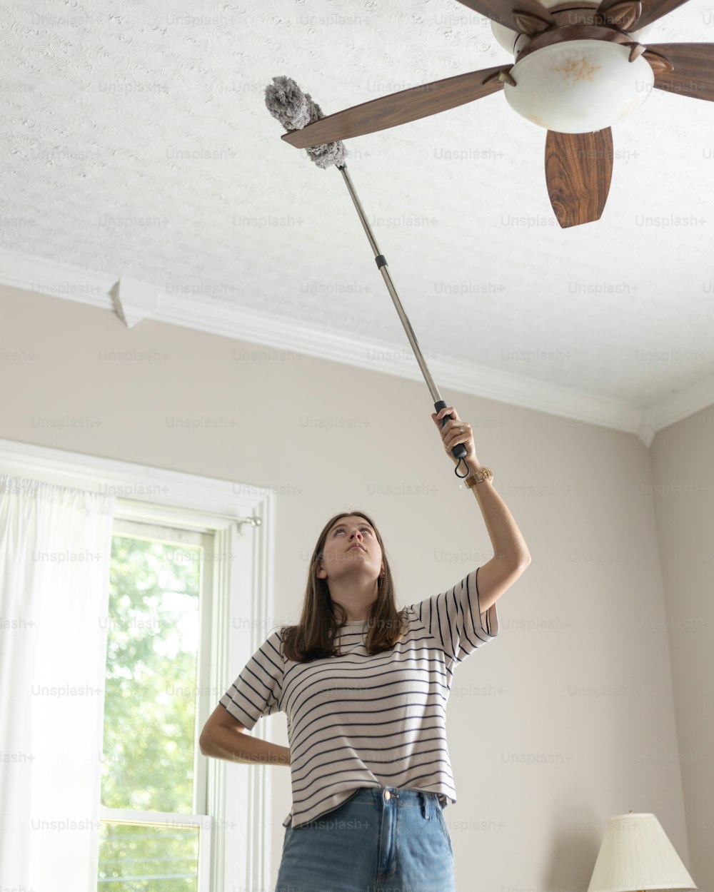 a woman holding a ceiling fan in a room