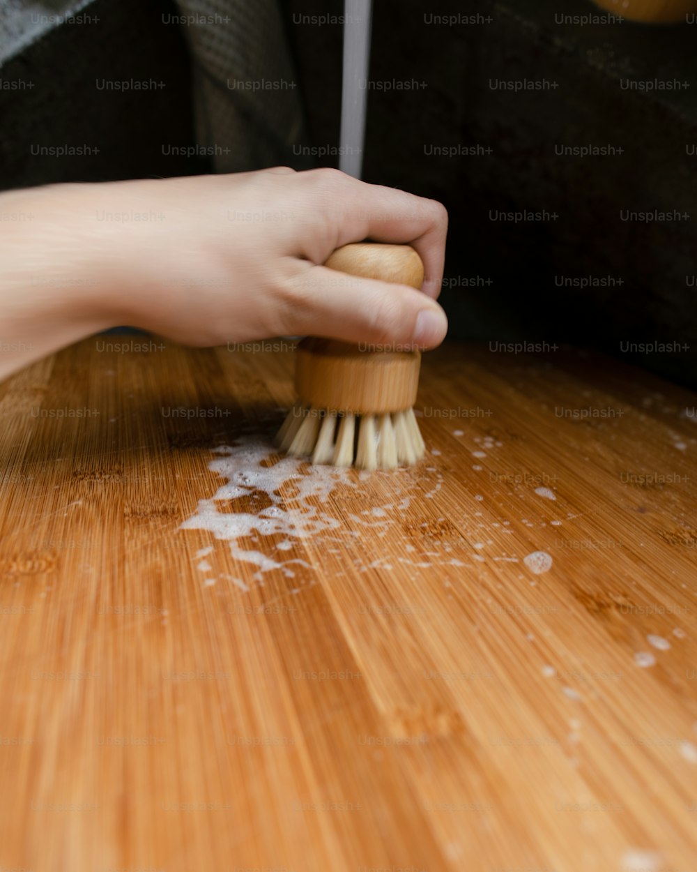uma pessoa está limpando uma mesa de madeira com uma escova