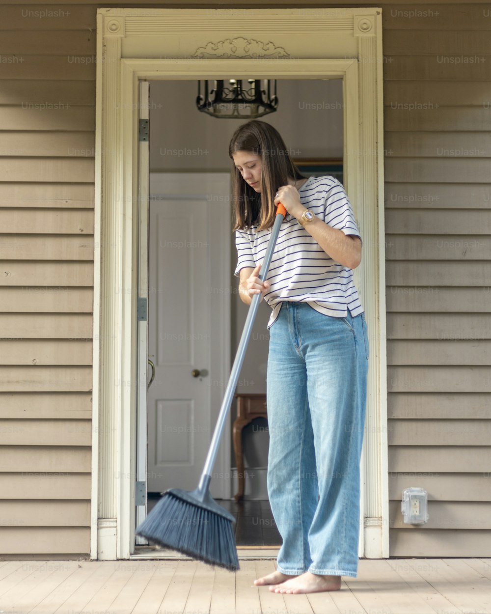 a woman standing on a porch with a broom