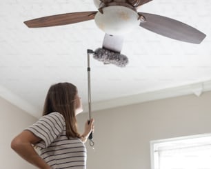 a woman standing in a room with a ceiling fan