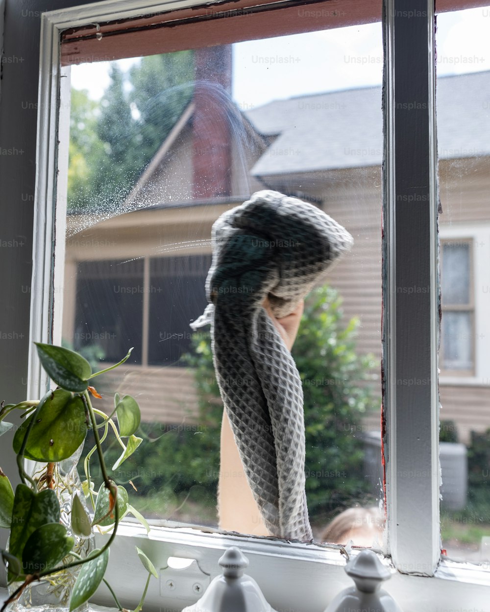 a woman looking out a window at a house