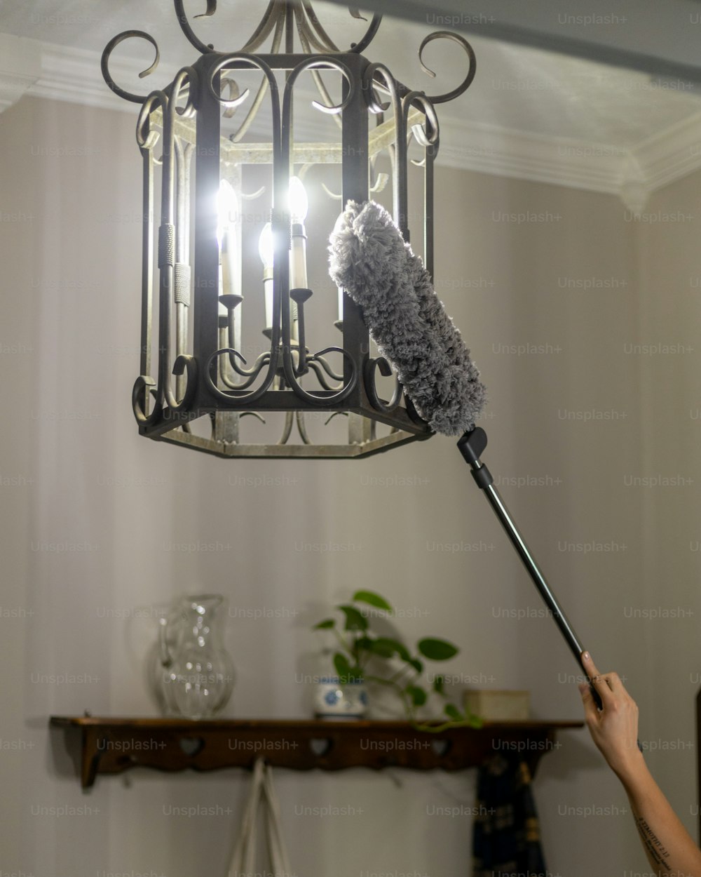 a person is holding a duster in front of a chandelier