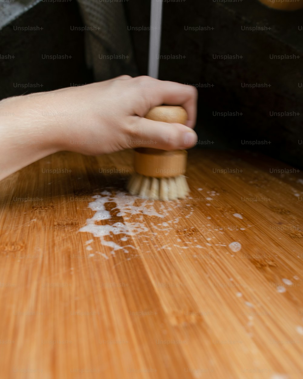 a person is cleaning a wooden table with a brush