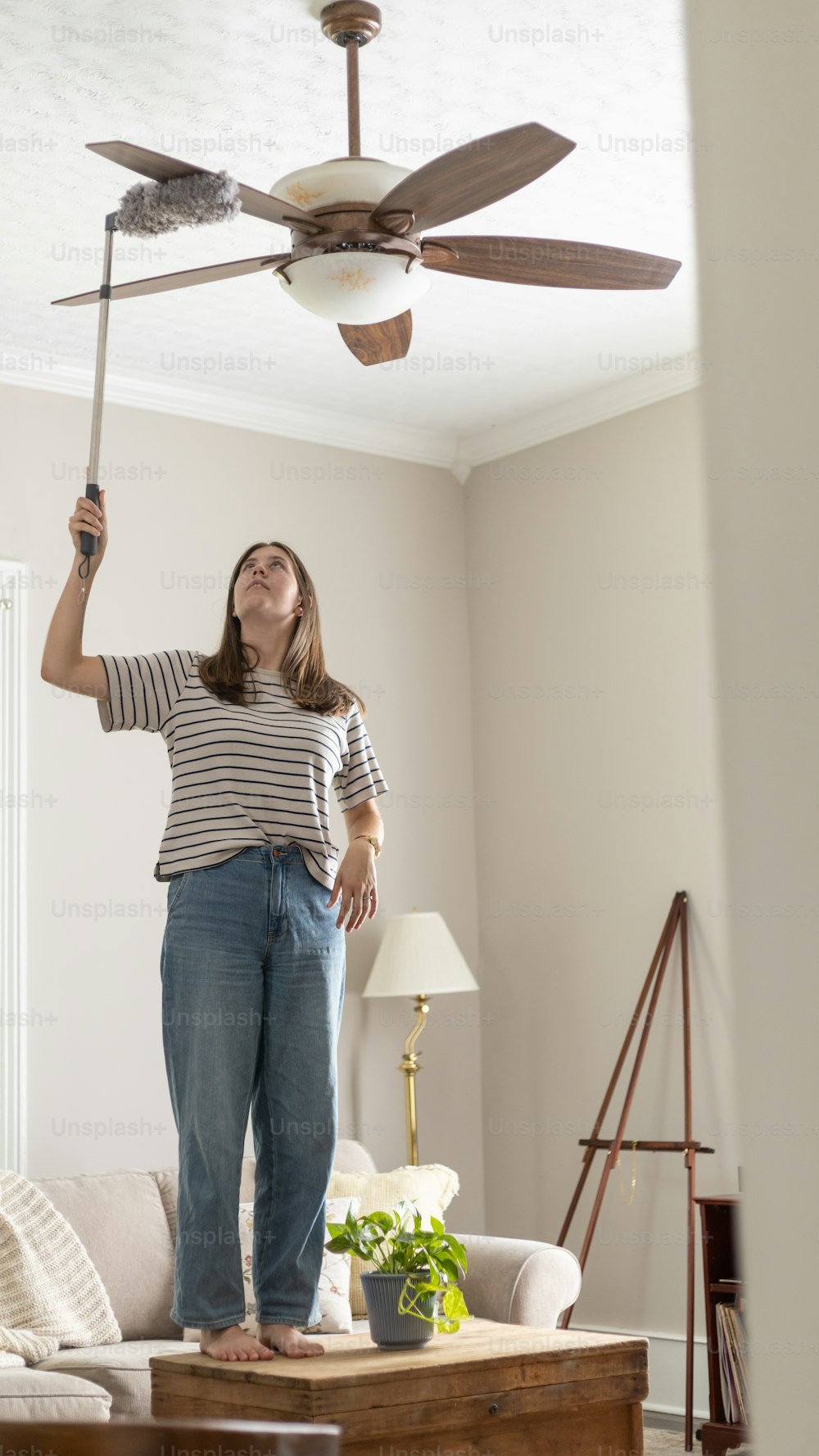 a woman holding a ceiling fan in a living room