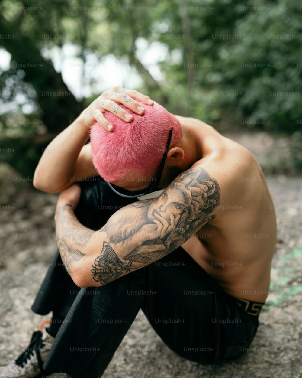 a man with a pink mohawk sitting on a rock