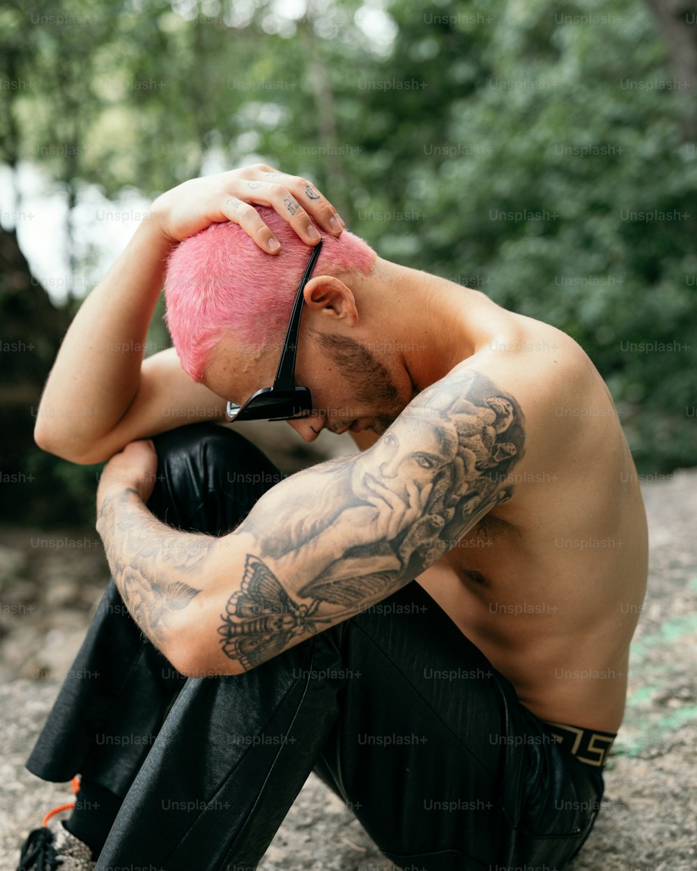 Un hombre con un mohawk rosa sentado en una roca