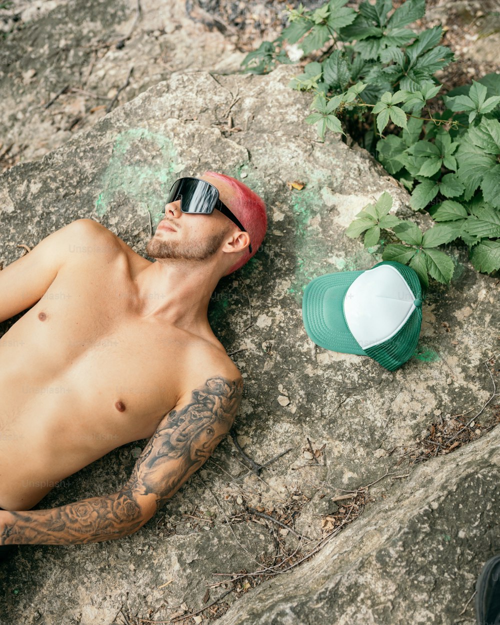 a shirtless man laying on top of a rock