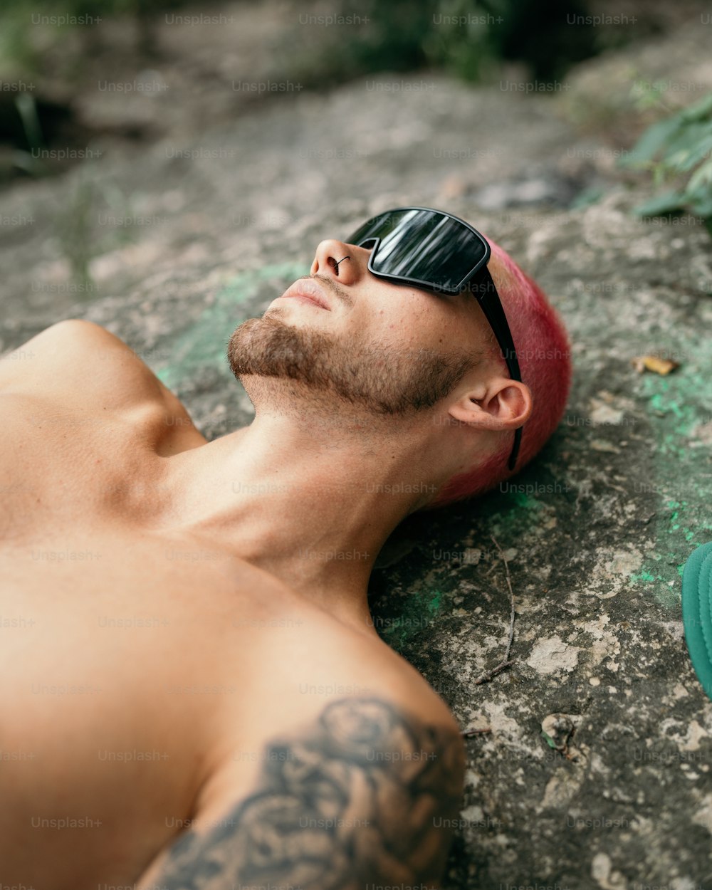 Un homme torse nu allongé sur le sol portant des lunettes de soleil