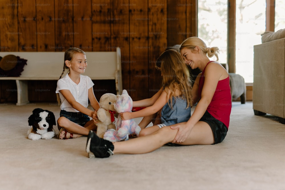 three girls sitting on the floor with stuffed animals