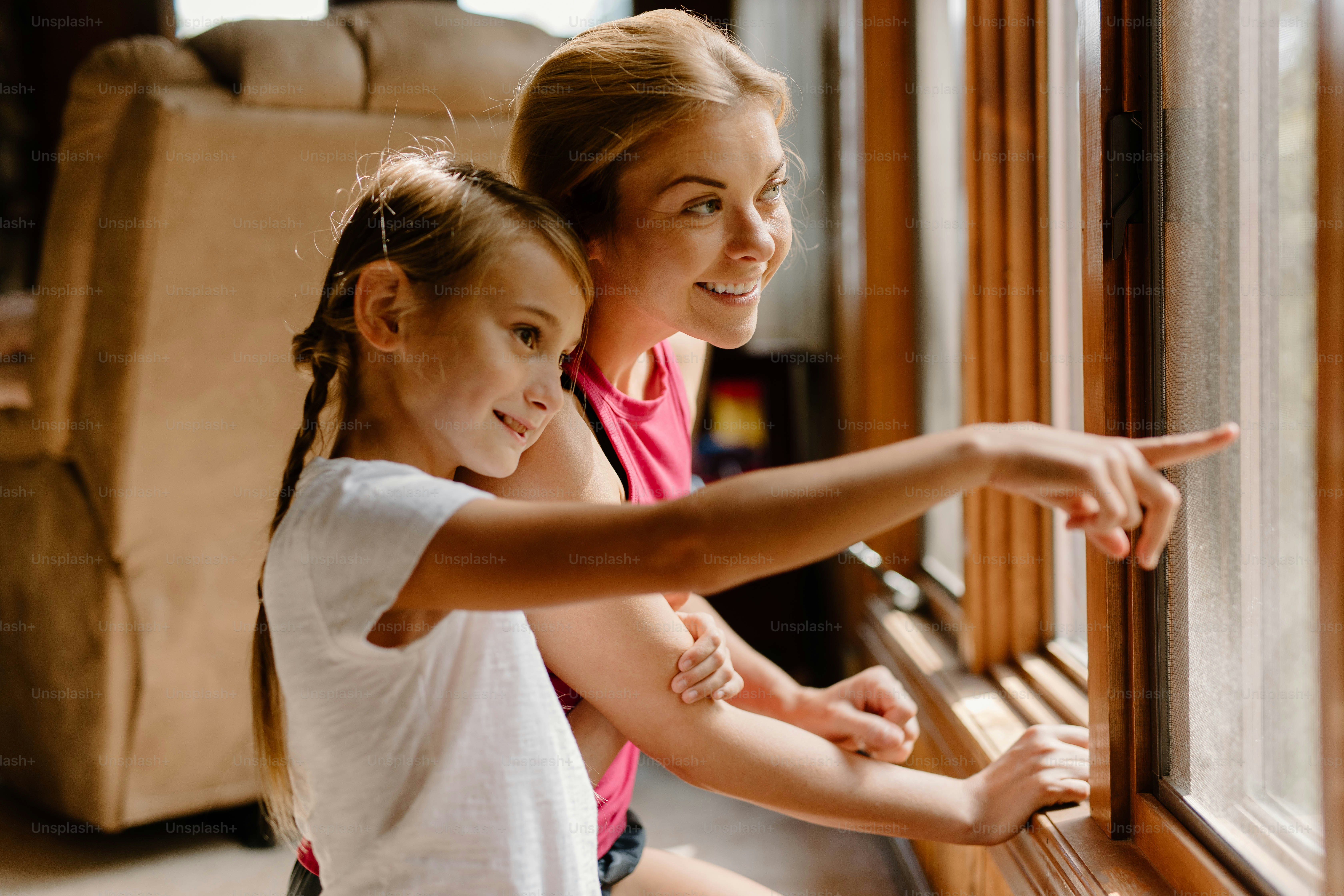 two young girls looking out of a window