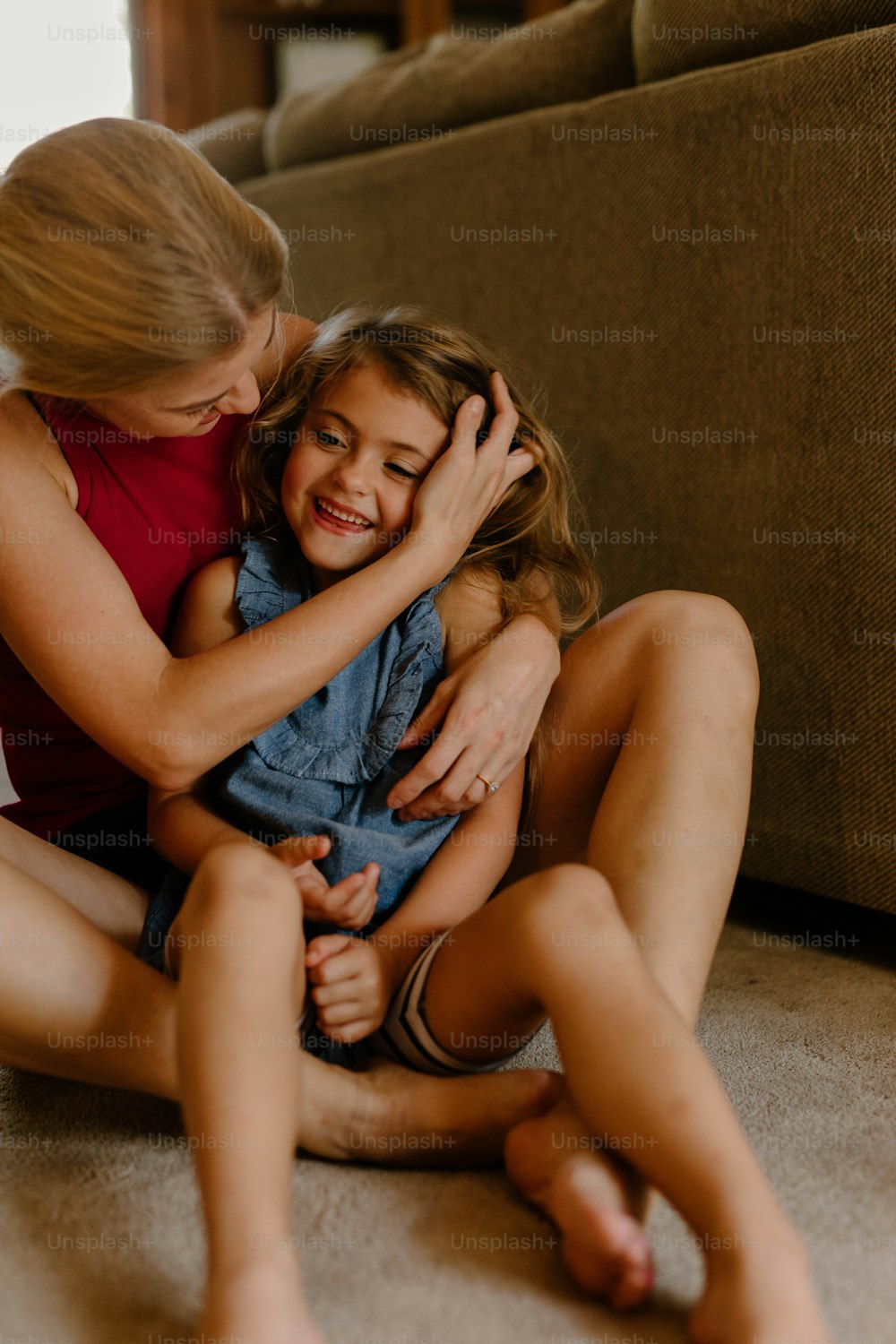 a woman sitting on the floor hugging a little girl
