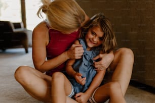 a woman sitting on the floor holding a little girl