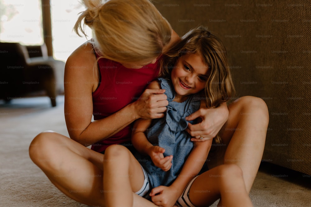 a woman sitting on the floor holding a little girl