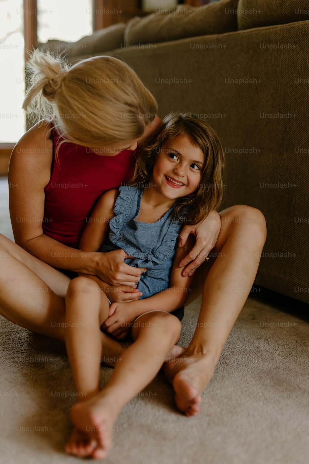 a woman sitting on the floor hugging a little girl
