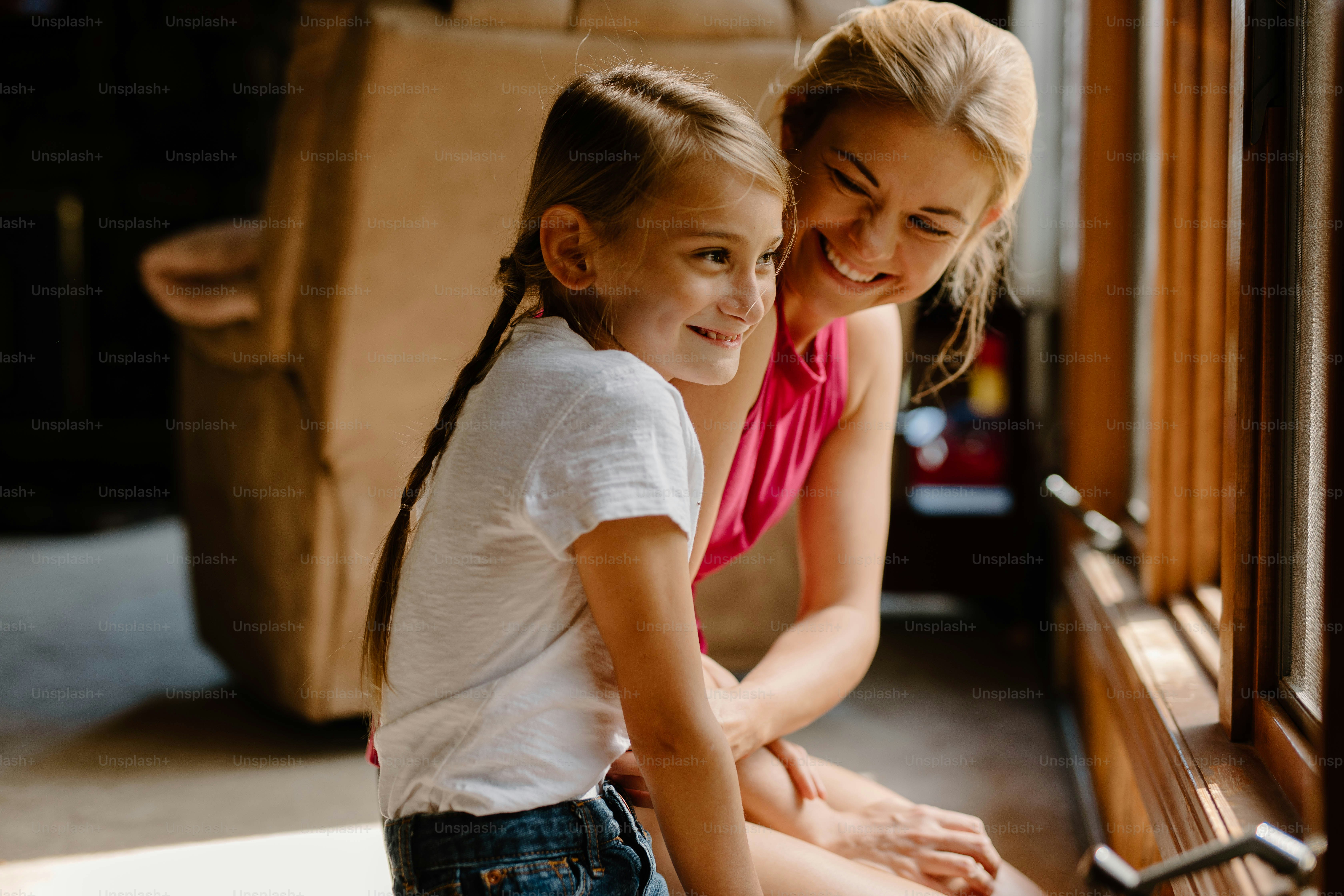 a girl and a girl sitting on a window sill