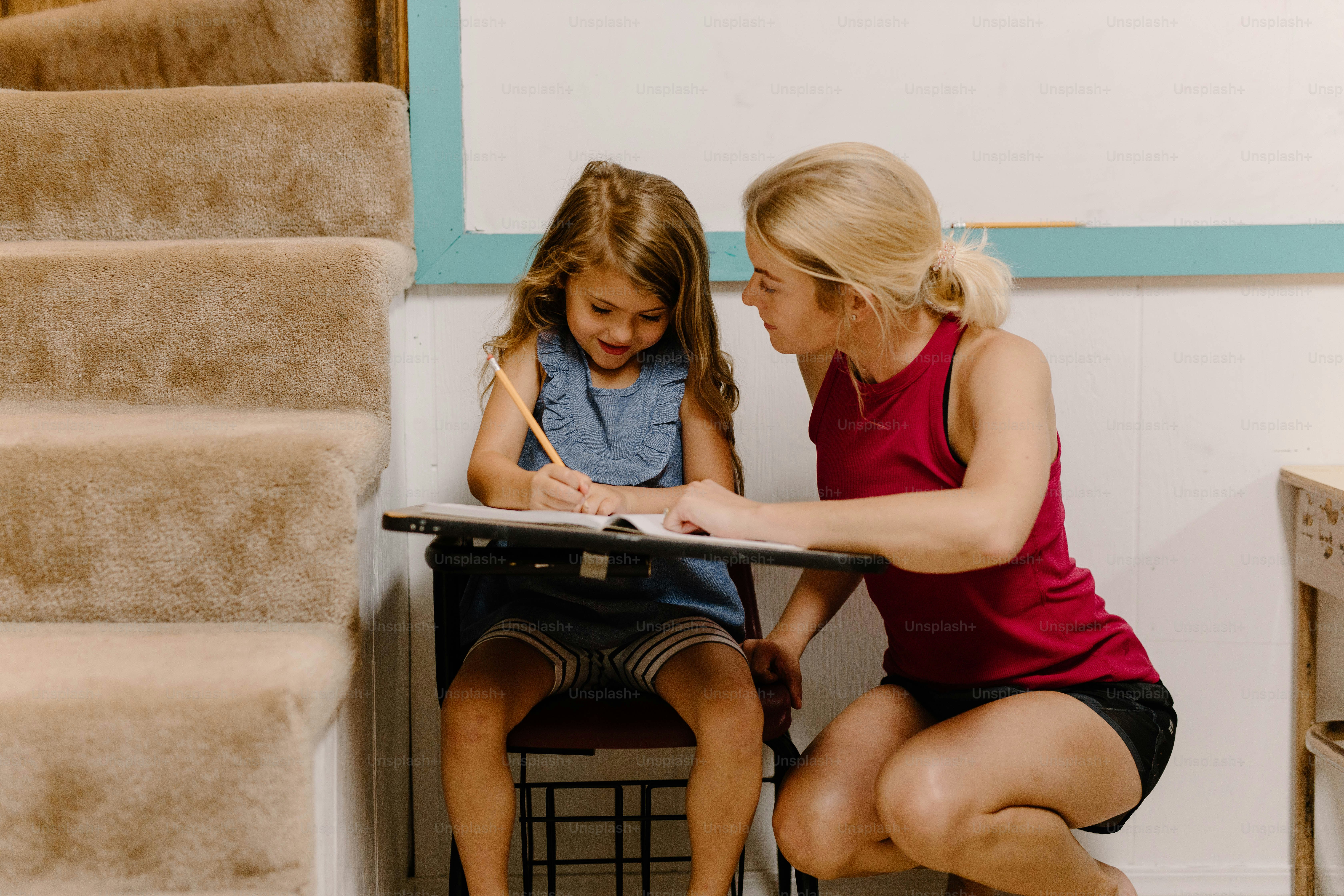 a woman sitting next to a little girl at a desk