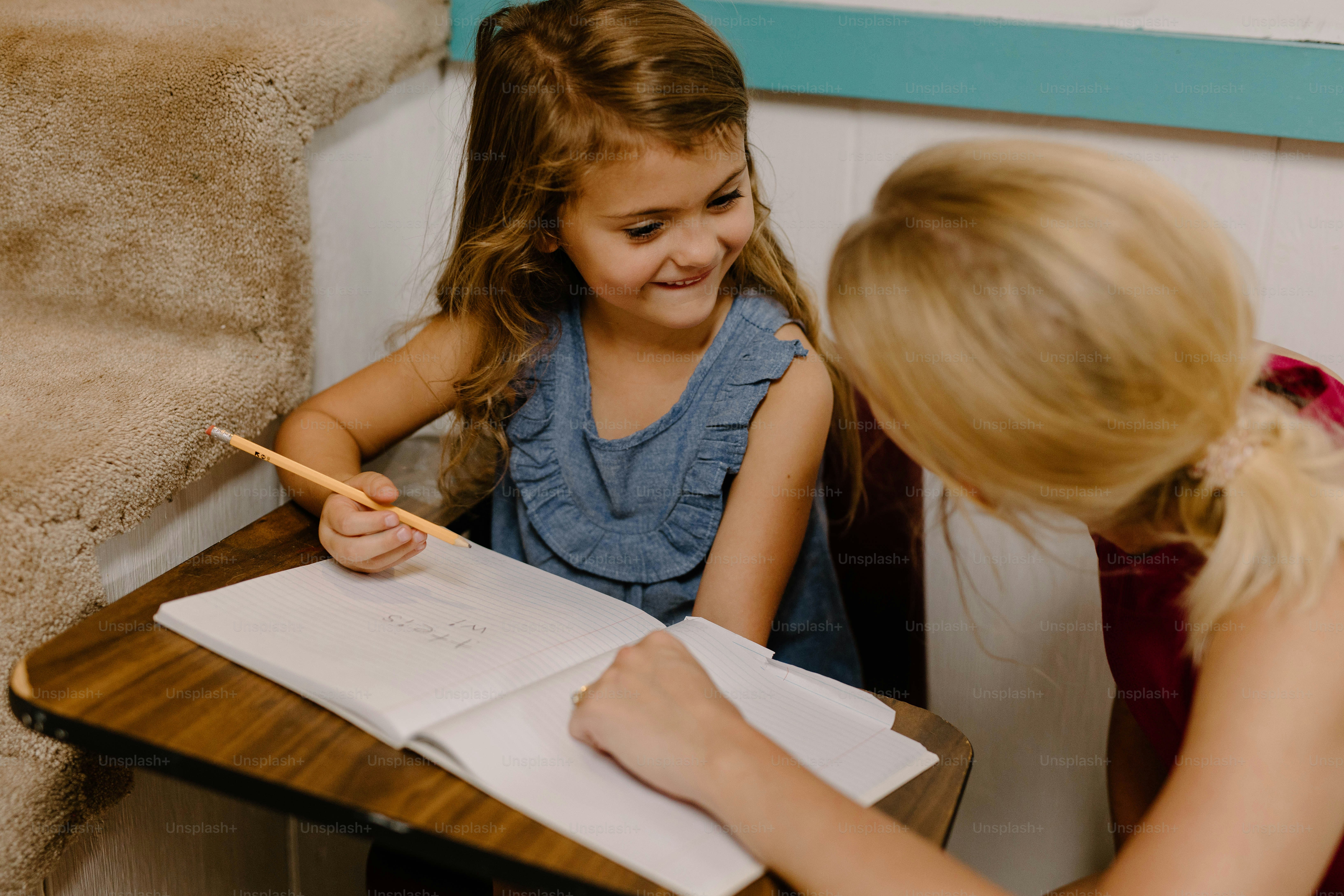 a little girl sitting at a desk writing on a piece of paper
