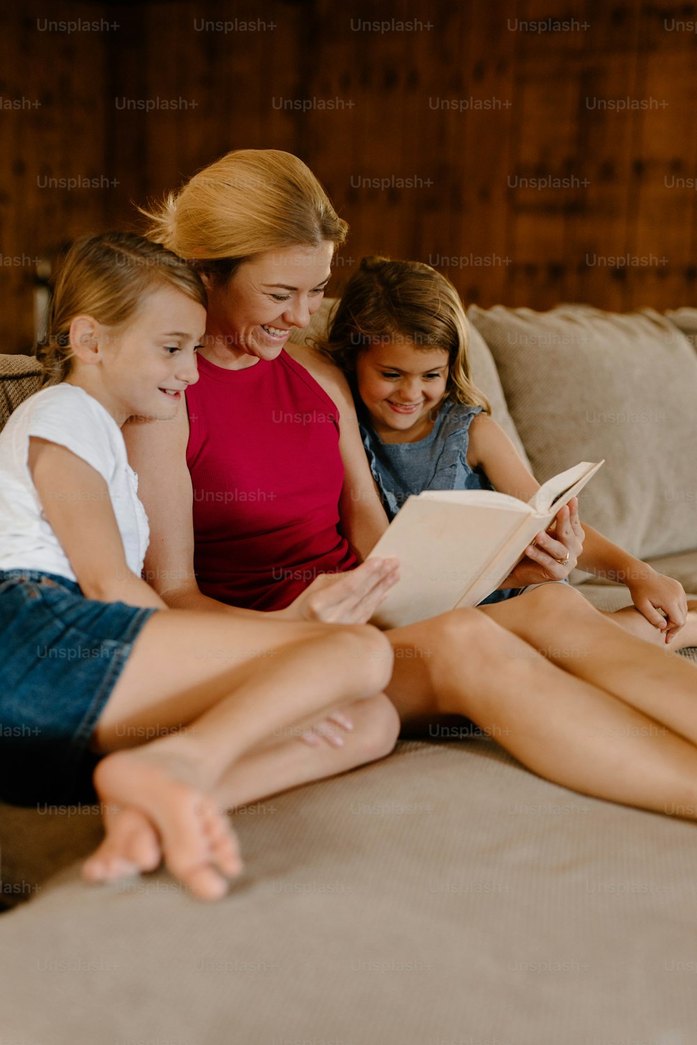 한 여자와 두 소녀가 침대에 앉아 책을 읽고 있다