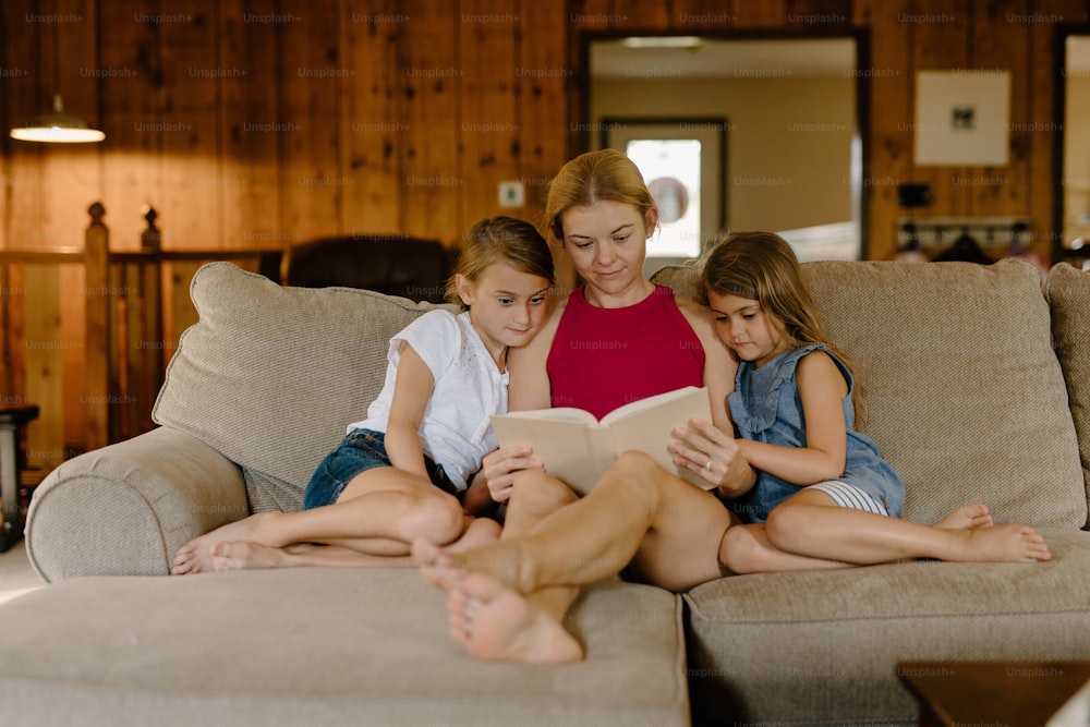 três meninas sentadas em um sofá lendo um livro
