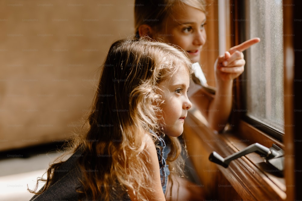 Zwei kleine Mädchen, die aus einem Fenster schauen