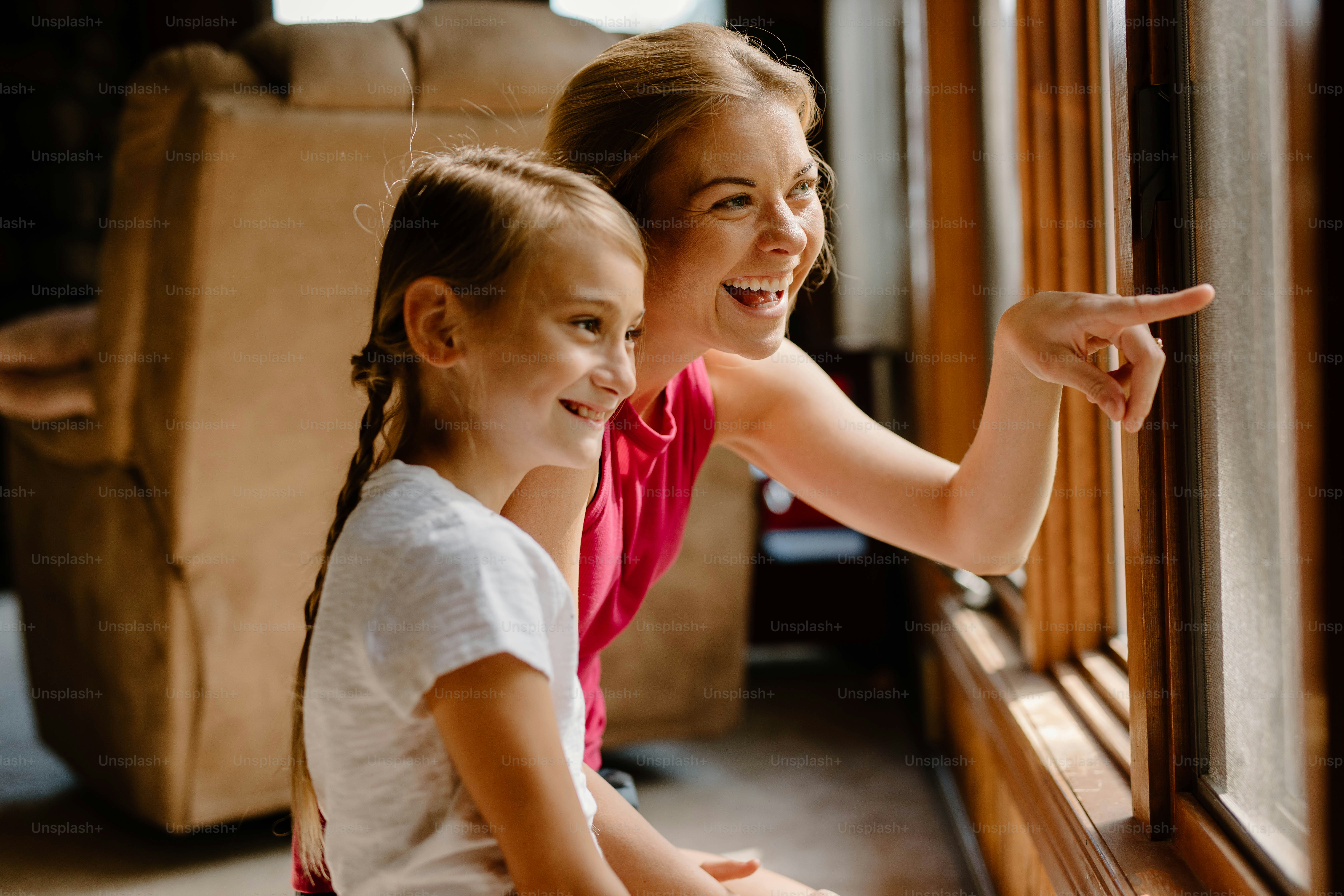 two young girls looking out of a window