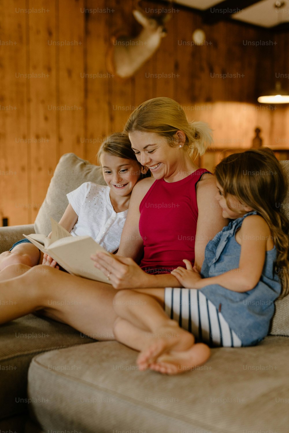 Eine Frau und zwei Mädchen sitzen auf einer Couch und lesen ein Buch