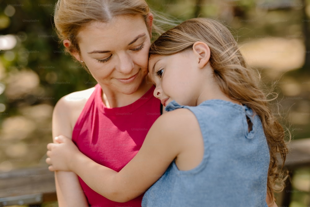 a woman hugging a little girl in a park