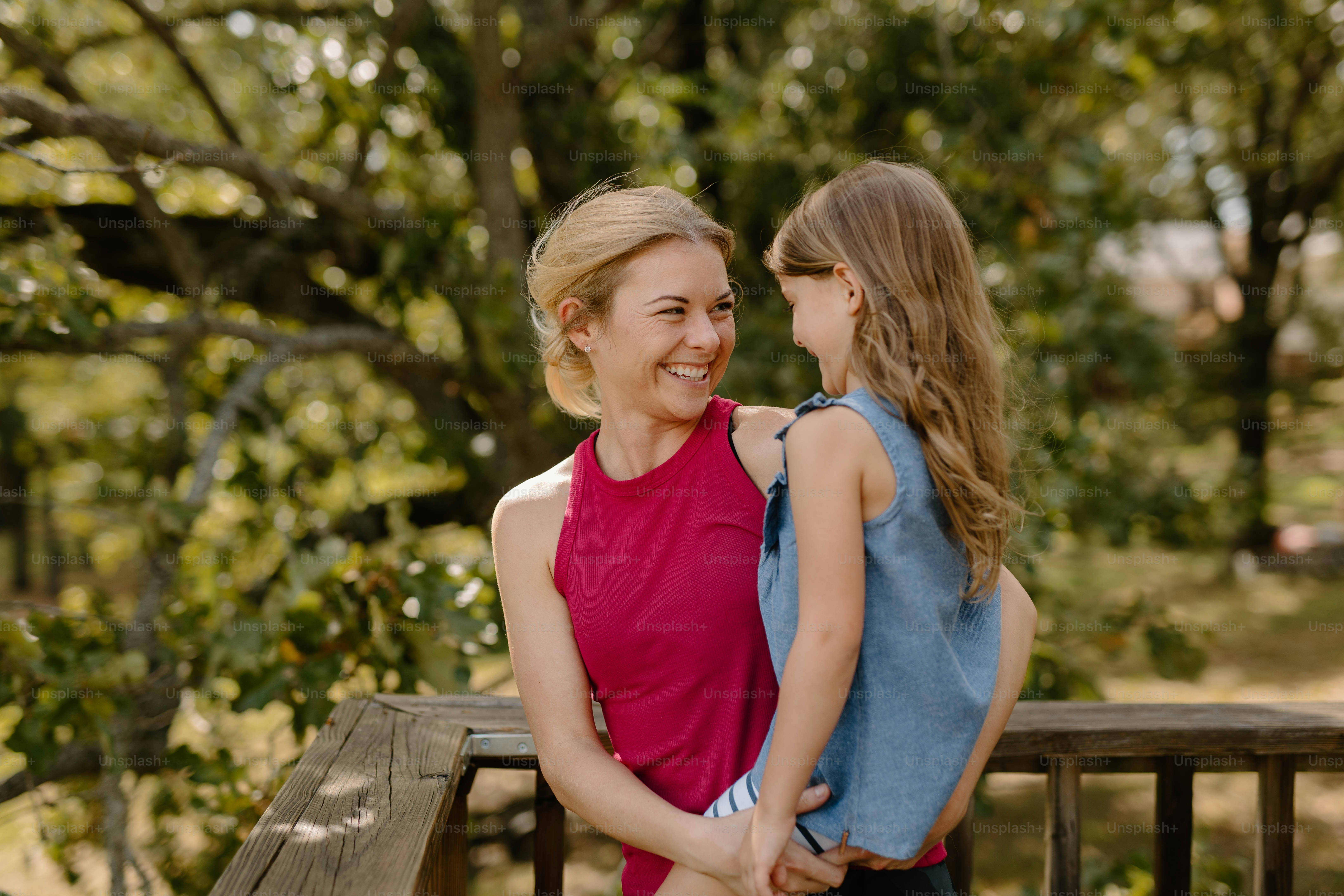 a woman and a little girl standing next to each other on a wooden bench