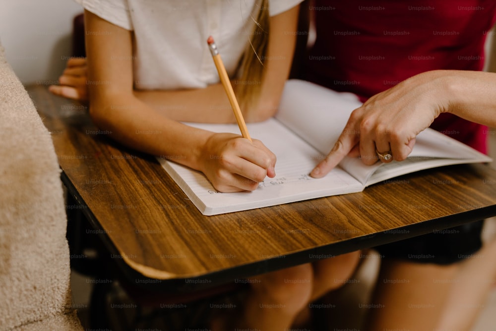 duas pessoas sentadas em uma mesa com um caderno e caneta
