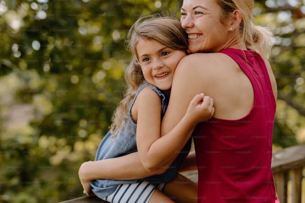 a woman hugging a little girl on the back of a bench