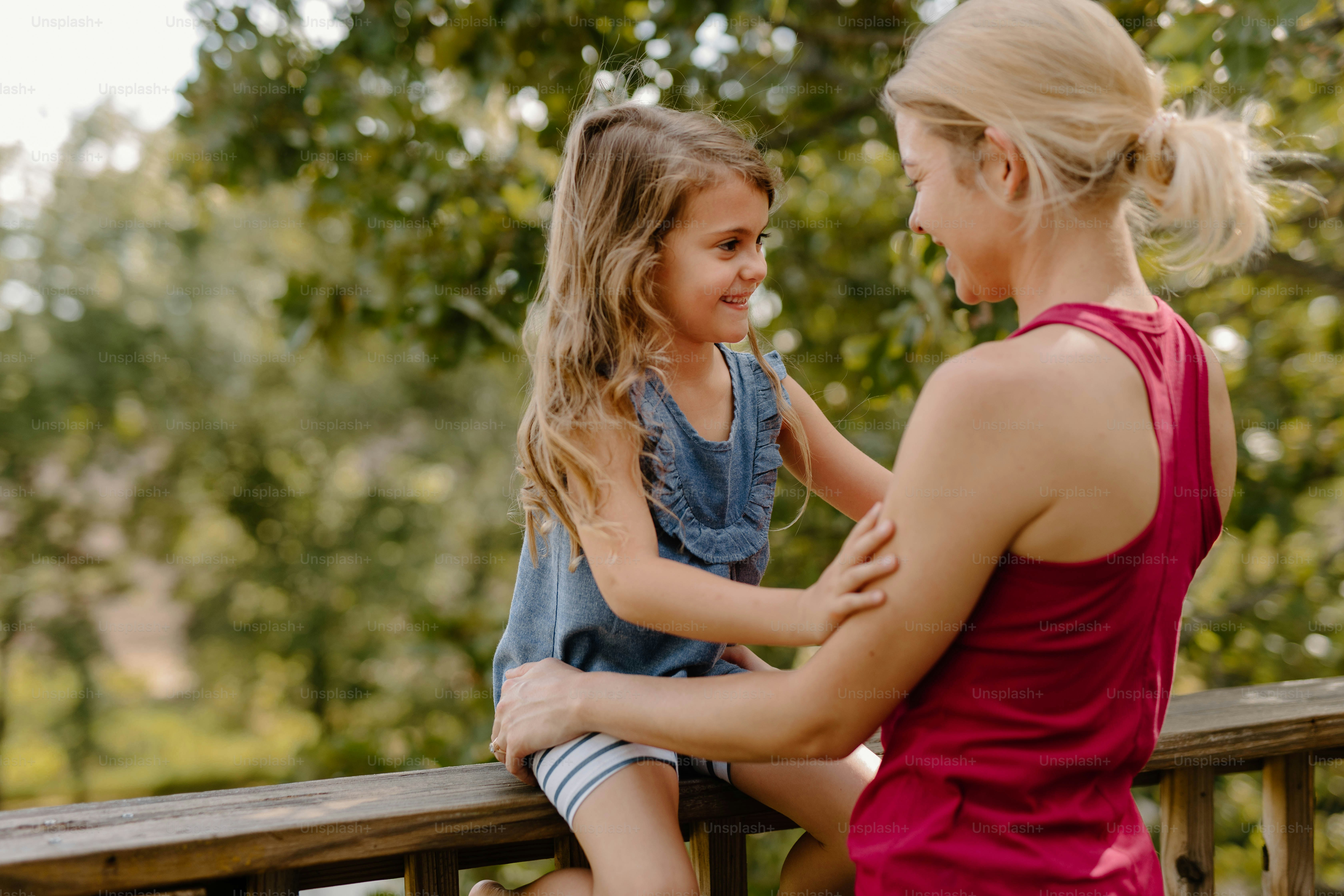 a woman and a little girl sitting on a wooden bench