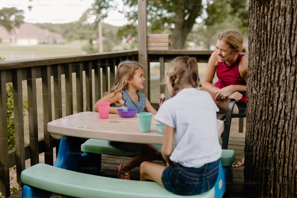 uma mulher e duas crianças sentadas em uma mesa de piquenique