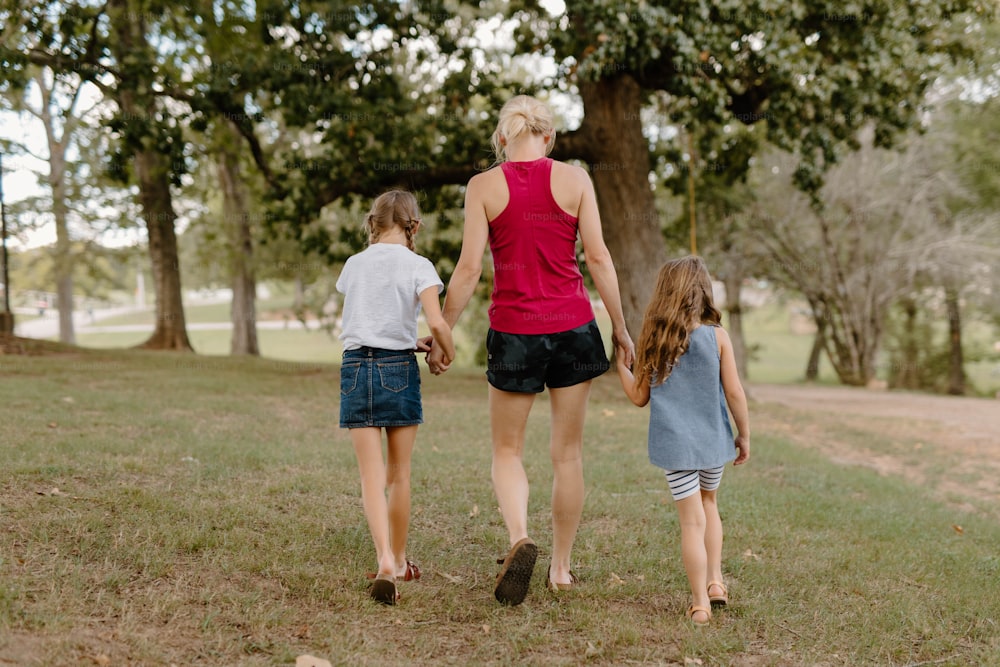 Une femme et deux enfants marchant dans un parc