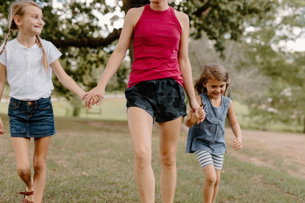 a woman and two children walking in a park