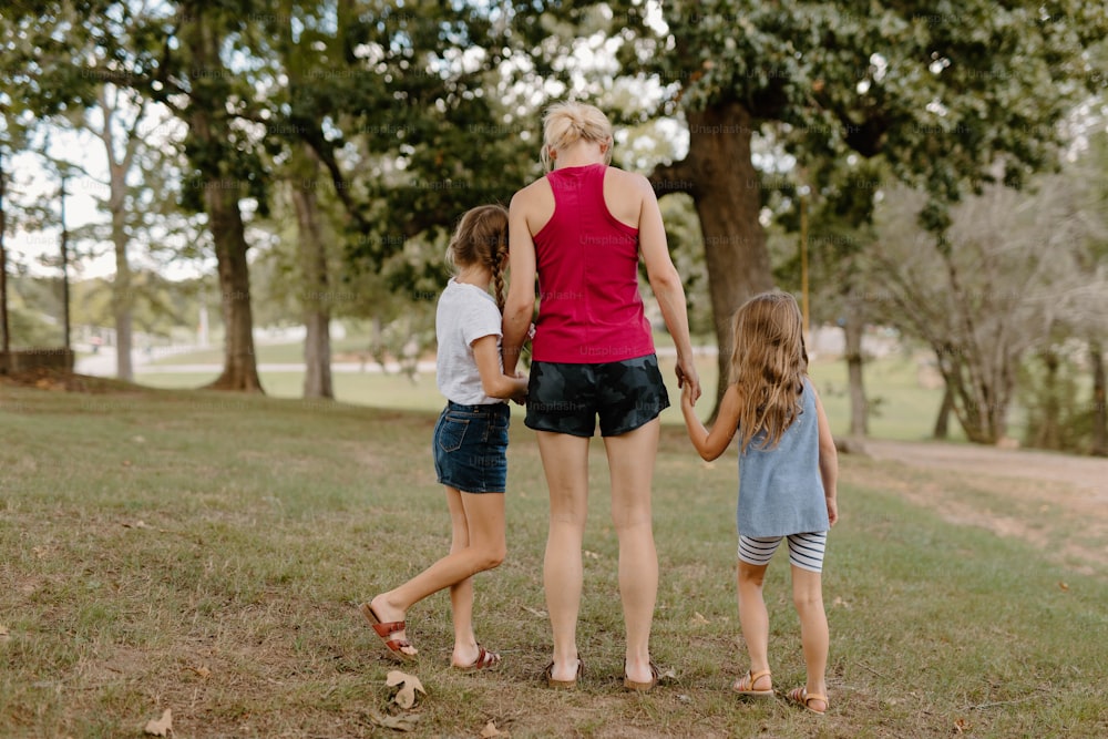 a woman and two children walking in a park