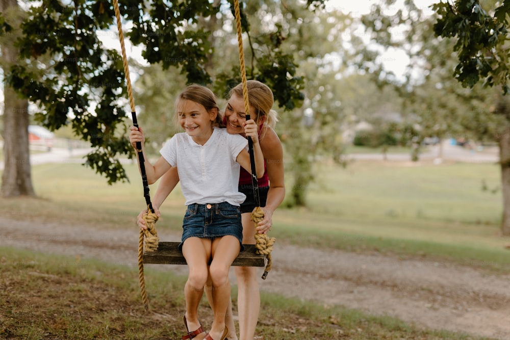 duas meninas sentadas em um balanço em um parque