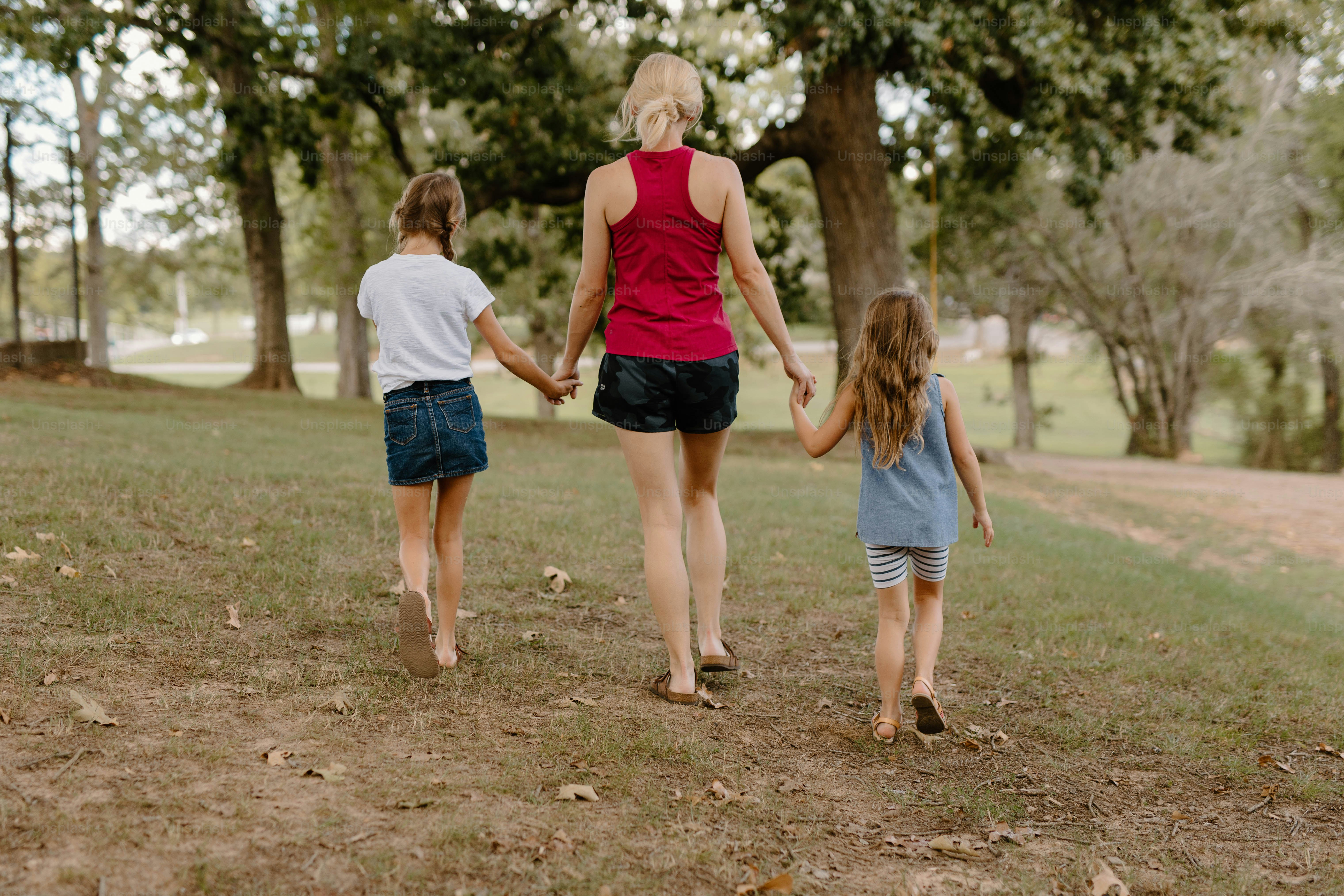 a woman and two children walking in a park