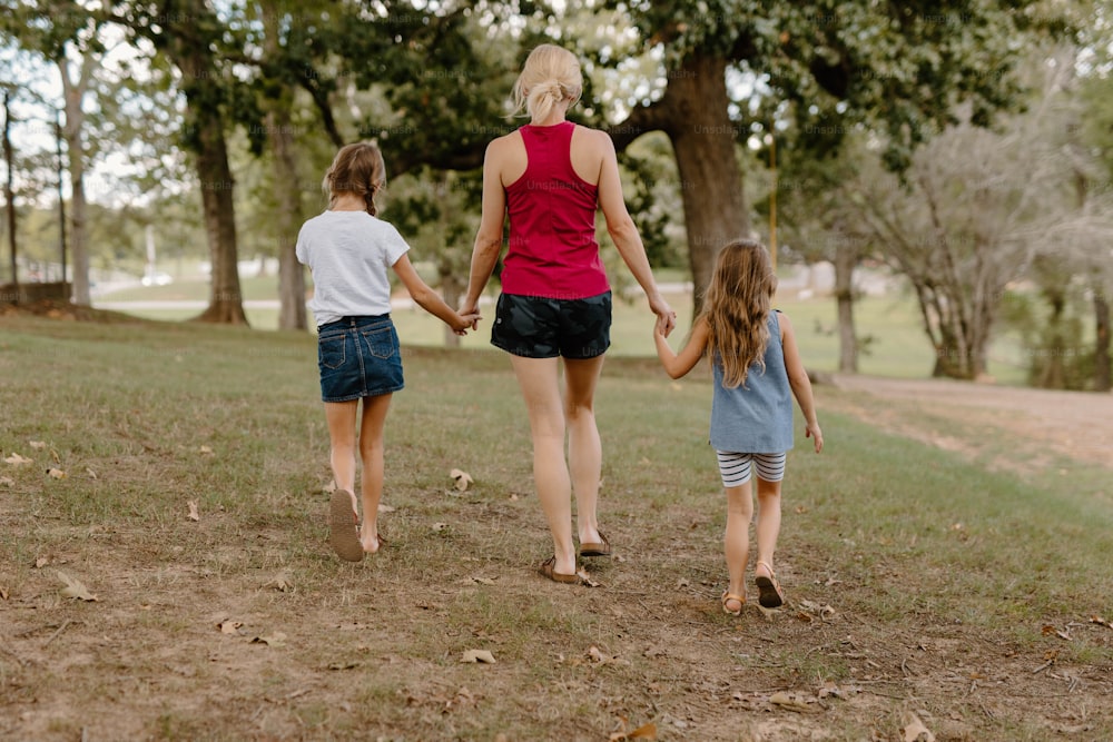 한 여자와 두 아이가 공원을 걷고 있다