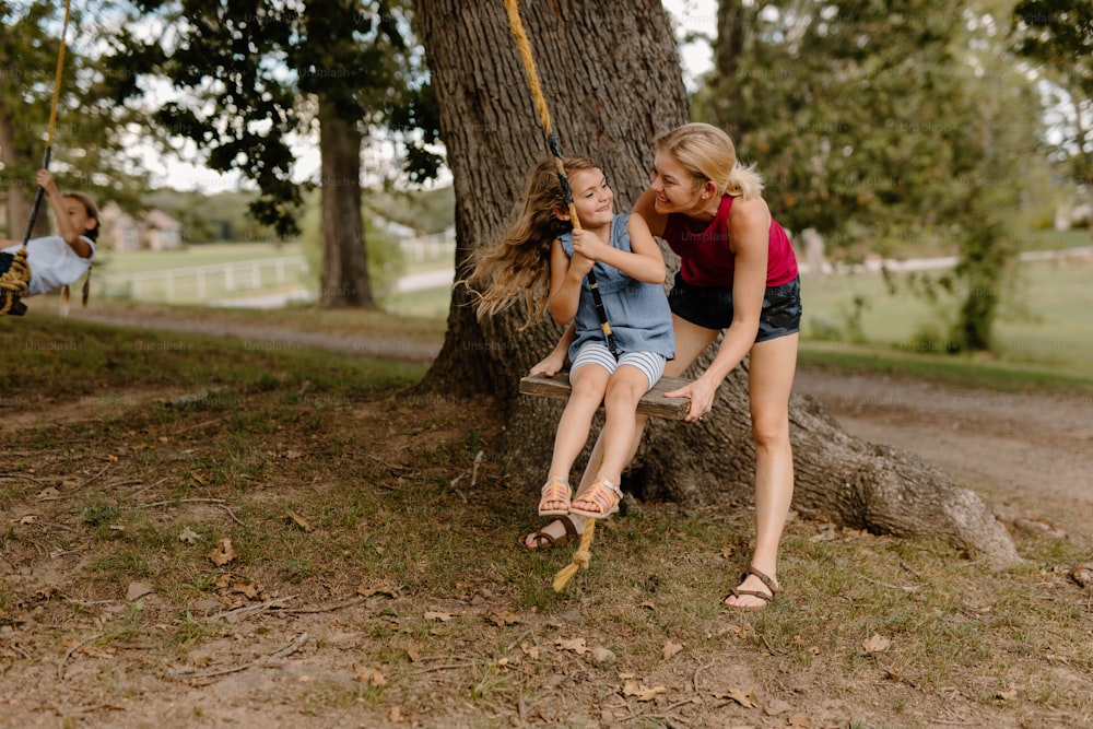 two girls sitting on a swing in a park