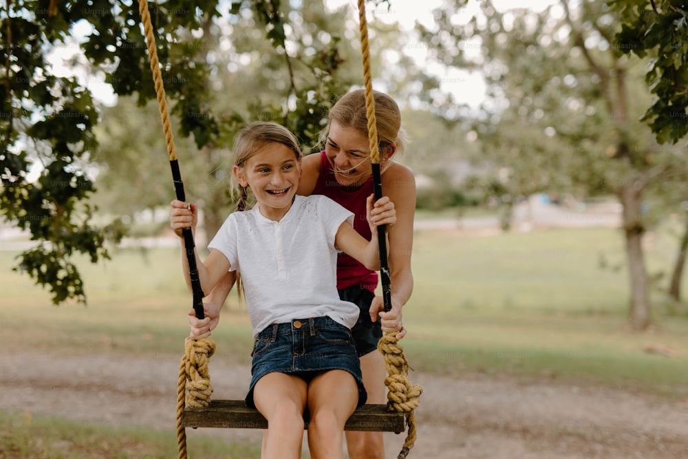 a woman sitting on a swing with a little girl