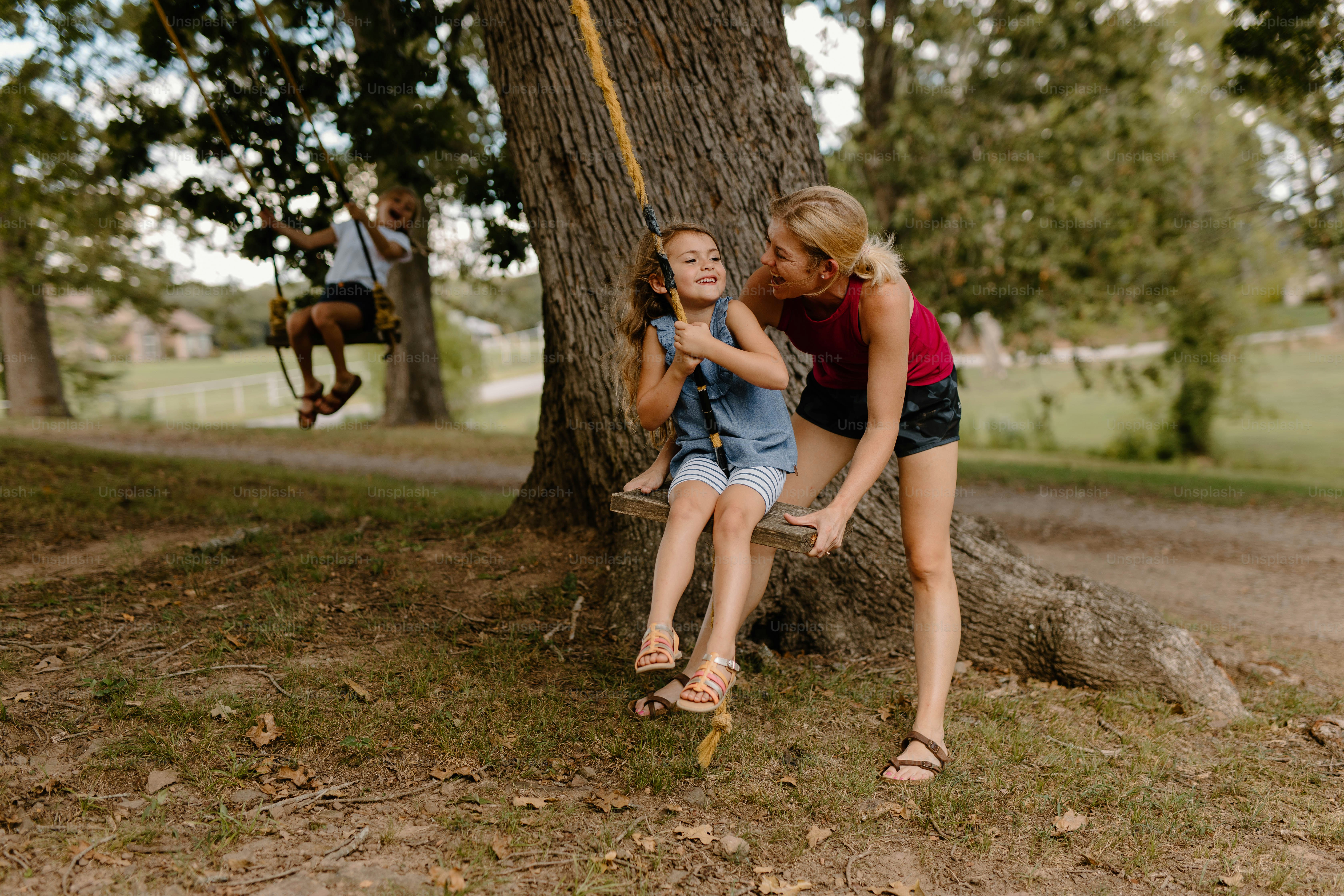 two girls sitting on a swing in a park