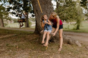 two girls sitting on a swing in a park