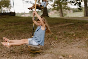 a little girl sitting on a swing in a park