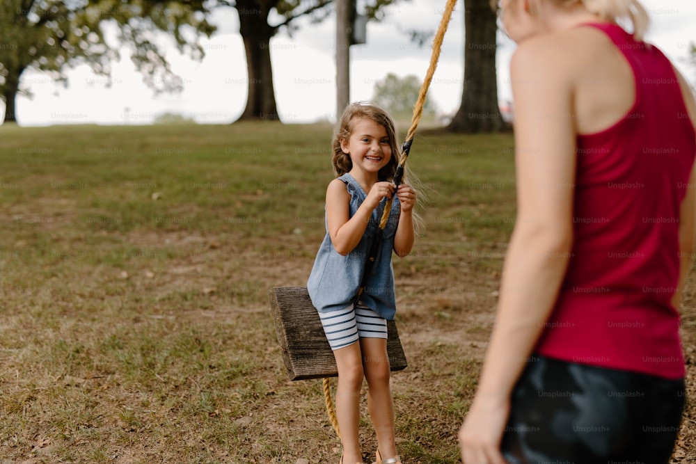 Una niña pequeña sosteniendo un bate de béisbol junto a una mujer