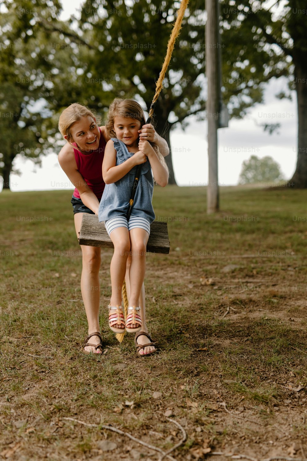 two young girls playing on a swing in a park