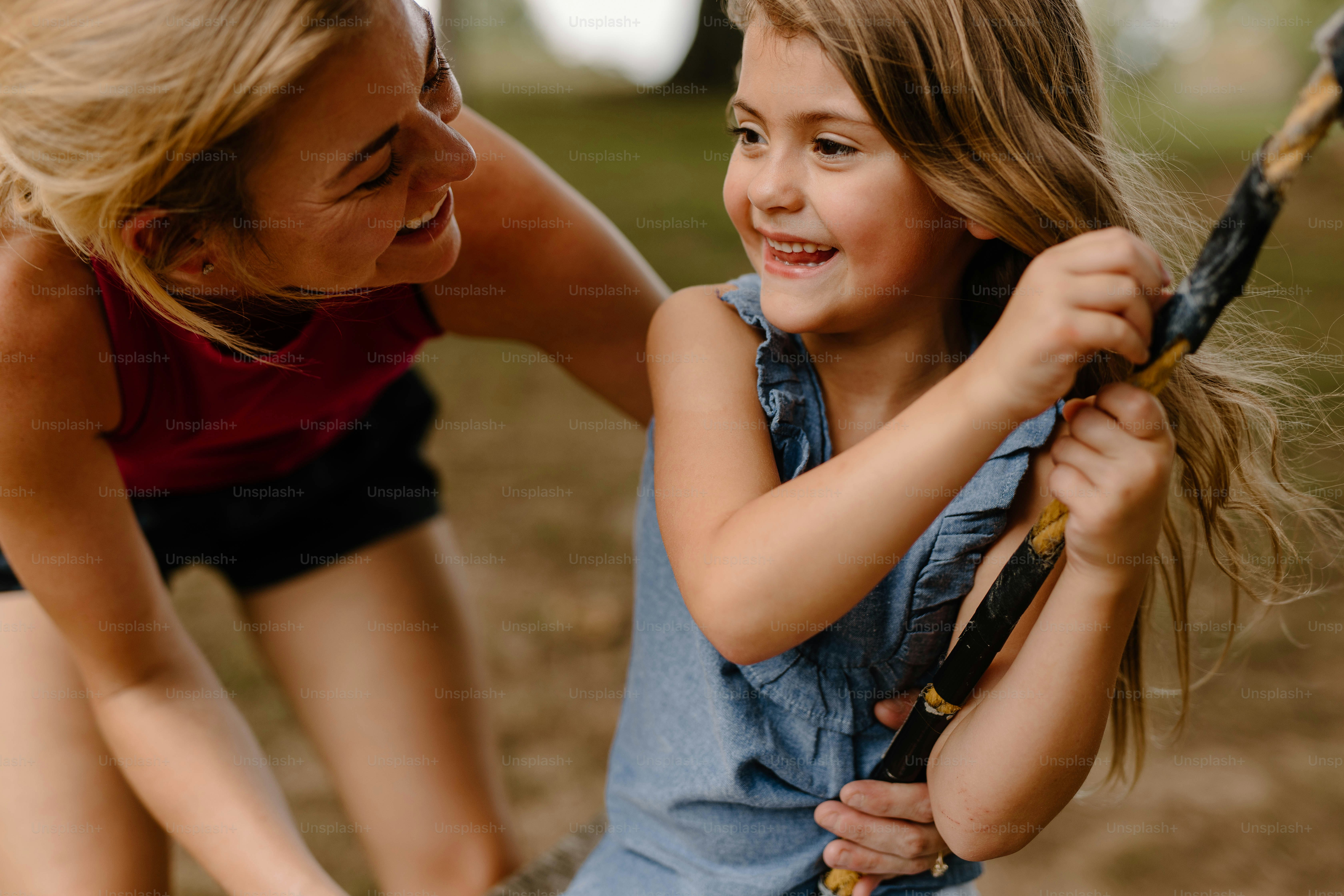 Una mujer ayudando a una niña con un bate de béisbol